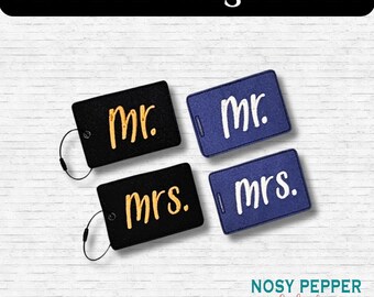 May include: Four luggage tags with the words "mr." and "mrs." embroidered on them. The tags are black and blue with gold and white lettering.