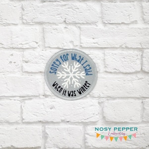 May include: A round, gray embroidered patch with a snowflake design and the text "Sorry for what I said when it was winter".