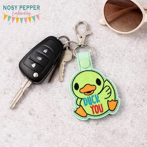 May include: A white ceramic mug with a black handle and the text "But First, Coffee" in a bold, black font. The mug is set against a blurred background, highlighting its clean design.