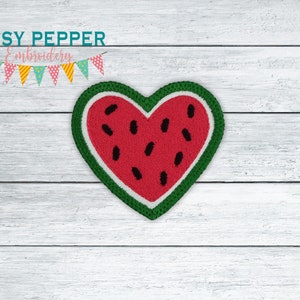 May include: An embroidered watermelon heart patch in red and green. The watermelon is cut in half and has black seeds. The patch is on a white wooden background.