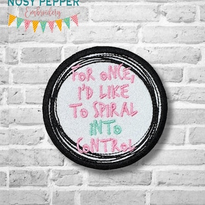 Op de afbeelding: Een witte geborduurde patch met zwarte stiksels rond de randen. De patch zegt "For once I'd like to spiral into control" in roze en turquoise letters.