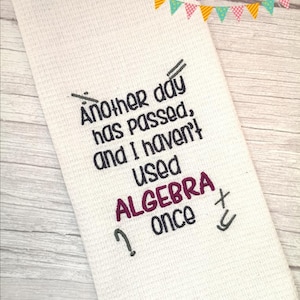 May include: White kitchen towel with the text "Another day has passed, and I haven't used ALGEBRA once" embroidered in black and purple.