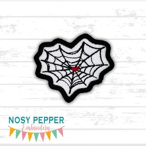May include: A black and white embroidered patch in the shape of a heart with a spider web design. A small red heart is in the center of the web.