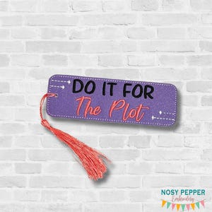 May include: Purple bookmark with the text "DO IT FOR The Plot" in black and red. The bookmark has a red tassel attached to the top left corner. The background is a white brick wall.