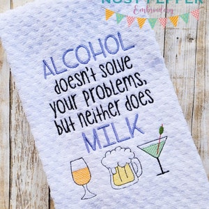 May include: White kitchen towel with the embroidered text "ALCOHOL doesn't solve your problems, but neither does MILK." Features illustrations of a wine glass, beer mug, and martini glass. The towel has a textured surface.