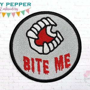 May include: A round gray embroidered patch with a white and red image of a set of teeth biting down. The text "Bite Me" is written in red below the teeth.