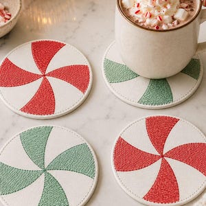 May include: Four round coasters with a candy cane design. Two have red and white stripes, and two have green and white stripes. A mug of hot chocolate with whipped cream and a candy cane sits on one coaster. Coasters are approximately 10 cm in diameter.