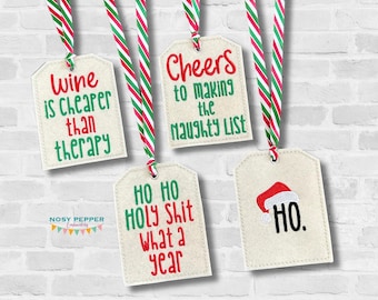 Peut inclure: Quatre étiquettes cadeaux sur le thème de Noël avec un ruban rouge et vert. Les étiquettes présentent les textes suivants : "Le vin est moins cher que la thérapie", "Santé pour avoir fait la liste des vilains", "Ho Ho Holy Shit What a Year", et "Ho".