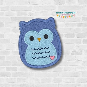 May include: A blue embroidered owl patch with a light blue center, black eyes, and a yellow beak. The owl has a heart and wavy lines. The patch is on a white brick background. The text "Nosy Pepper Embroidery" is at the top.