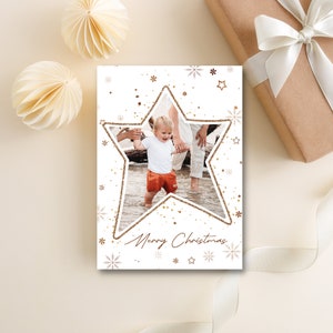 Könnte beinhalten: Eine weiße Weihnachtskarte mit einer goldenen Glitzersternform. Der Stern enthält ein Foto eines Kindes und zweier Erwachsener. Der Text "Merry Christmas" ist in Kursivschrift am unteren Rand der Karte geschrieben.