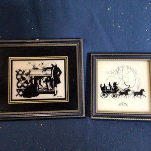 May include: Two framed black and white silhouette artwork prints. The first print depicts a couple in a carriage pulled by horses. The second print shows a woman playing a piano.