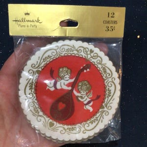 May include: A package of 12 coasters with a red and white design. Each coaster features a red circle with two cherubs and a lute, surrounded by a gold and white decorative border. The package is labeled "Hallmark Plans-a-Party."