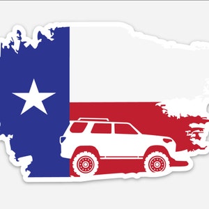 Puede incluir: Una pegatina con el diseño de la bandera del estado de Texas con una silueta de SUV blanca. La bandera tiene la forma de Texas, con un campo azul y una estrella blanca, y rayas rojas y blancas. El SUV es blanco.