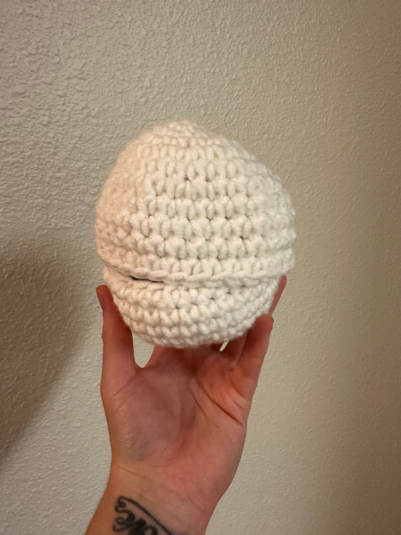Puede incluir: Un gorro blanco de ganchillo con un borde doblado.