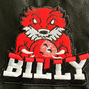 K&ouml;nnte beinhalten: Gestickter Aufn&auml;her mit einem roten Comic-Fuchs, der einen roten Ball h&auml;lt, mit dem Wort "BILLY" in wei&szlig;en Buchstaben auf schwarzem Hintergrund.