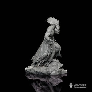 Puede incluir: Una figura de resina gris de una criatura humanoide con cabeza de tentáculos, túnicas fluidas y brazos extendidos. La figura está posada sobre una base rocosa sobre un fondo negro. La figura está etiquetada como "MINIATURE E BUSTI in resina".