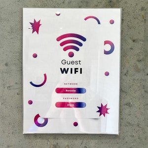 May include: A white sign with a pink and purple Wi-Fi symbol, the text "Guest WIFI", and the words "Network: Borcelle" and "Password: 01234".