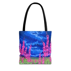Könnte beinhalten: Tragetasche mit einem lebendigen Gemälde von rosa Wildblumen vor einem tiefblauen Himmel mit strukturierten Pinselstrichen. Die Tasche hat einen schwarzen Griff und ein grünes Feld am Boden. Ein stilvolles und künstlerisches Accessoire.