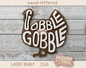 May include: A white turkey silhouette with the words "Gobble Gobble" written in a hand-lettered style. The design is laser-ready and comes in an SVG format.