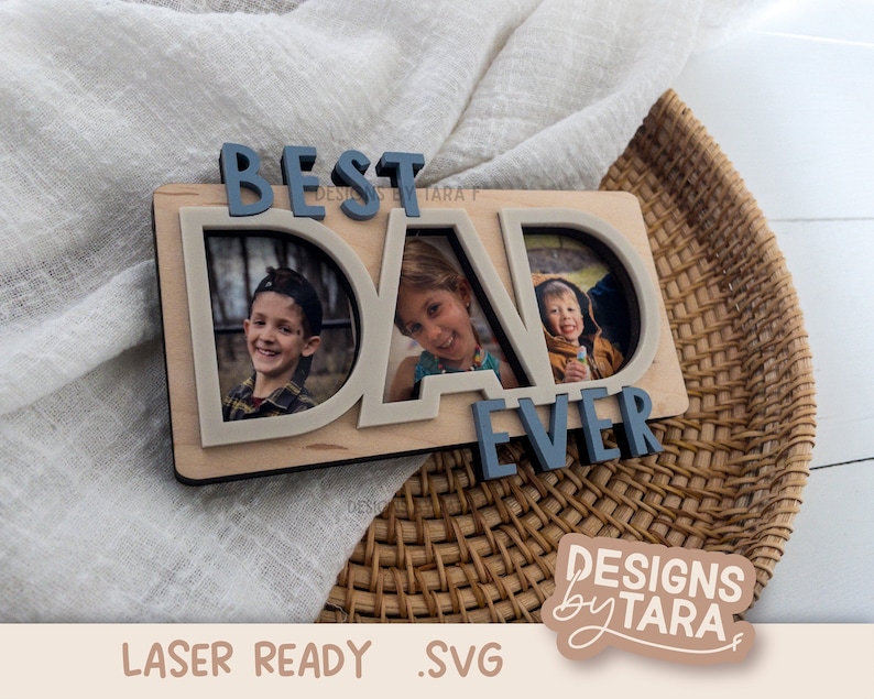 May include: A wooden sign with the words "Best Dad Ever" in blue letters. The sign has two photo frames with pictures of children inside. The sign is on a woven basket.