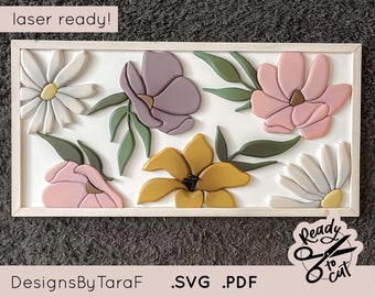 Può includere: Un design di arte da parete in legno tagliato al laser che presenta un arrangiamento floreale con fiori rosa, viola, gialli e bianchi. Il design è incorniciato in una cornice di legno bianca e include il testo "laser ready!" e "DesignsByTaraF .SVG .PDF".