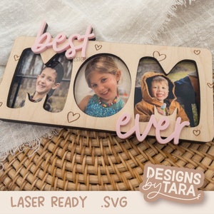 May include: Wooden photo frame with the words "best mom ever" in pink lettering. The frame has three cut-out spaces for photos and is decorated with small hearts.