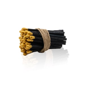 May include: A bundle of black matches with gold tips, tied together with twine.
