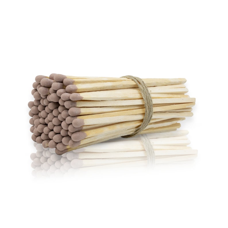 May include: A bundle of wooden matches with brown tips, tied together with twine. The matches are arranged in a rectangular shape and are reflected in a white surface.