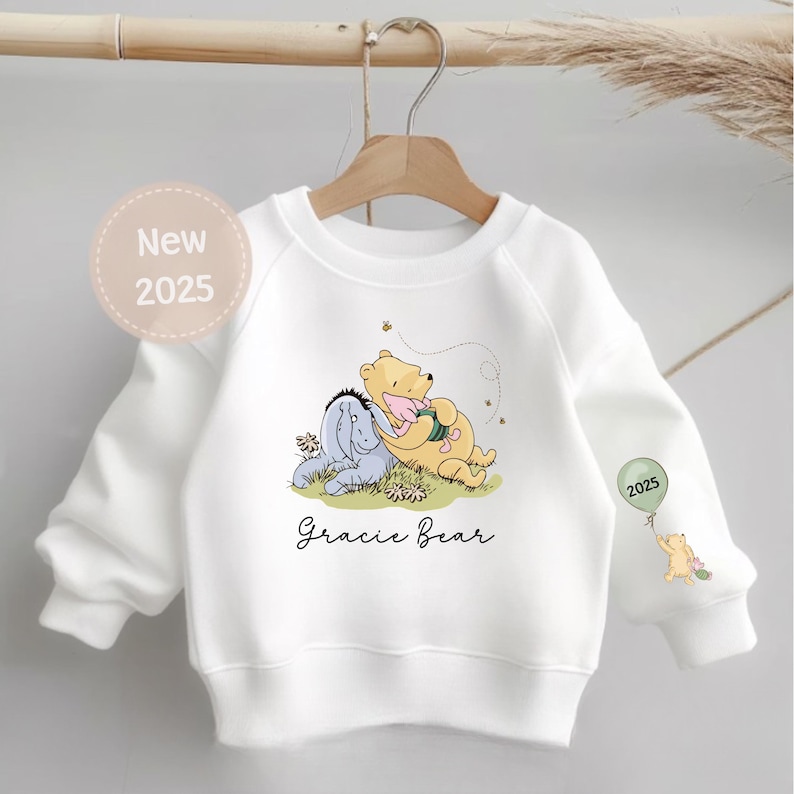 May include: White sweatshirt with a Winnie the Pooh and Piglet graphic, the text "Gracie Bear" and the year "2025" printed on it.