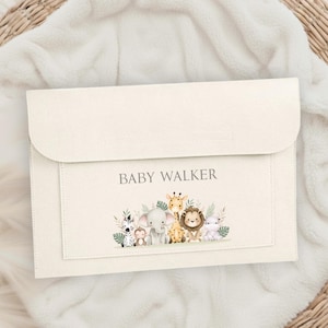 Può includere: Pochette per bambini color crema con la scritta "BABY WALKER" sopra un'illustrazione ad acquerello di animali della savana. La pochette ha una chiusura a patta e una tasca frontale con un bordo decorativo.