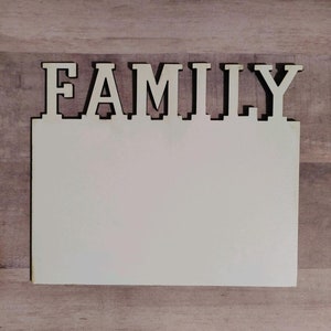 May include: A wooden sign with the word "FAMILY" in large, white letters. The sign has a blank, white surface below the word.