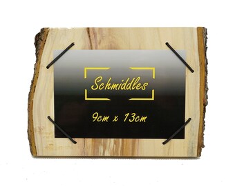 Könnte beinhalten: Ein Bilderrahmen aus Naturholz mit schwarzem Hintergrund und dem Text "Schmiddles 9cm x 13cm" in Gelb. Der Rahmen wird mit schwarzen Gummibändern zusammengehalten.