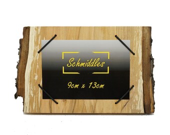 Könnte beinhalten: Ein rustikaler Holzbilderrahmen mit natürlichem Rindenrand. Der Rahmen hat einen schwarz-grauen Farbverlaufshintergrund mit dem Text "Schmiddles" und den Abmessungen 9 cm x 13 cm. Schwarze Kordeln sichern die Rückseite.