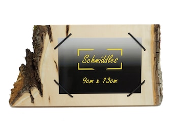 Könnte beinhalten: Rustikaler Holzbilderrahmen mit natürlichem Rindenrand. Der Rahmen enthält ein schwarzes und farbverlaufendes Bild, das mit schwarzen Gummischnüren befestigt ist. Der Text "Schmiddles" und "9cm x 13cm" sind in Gelb dargestellt.