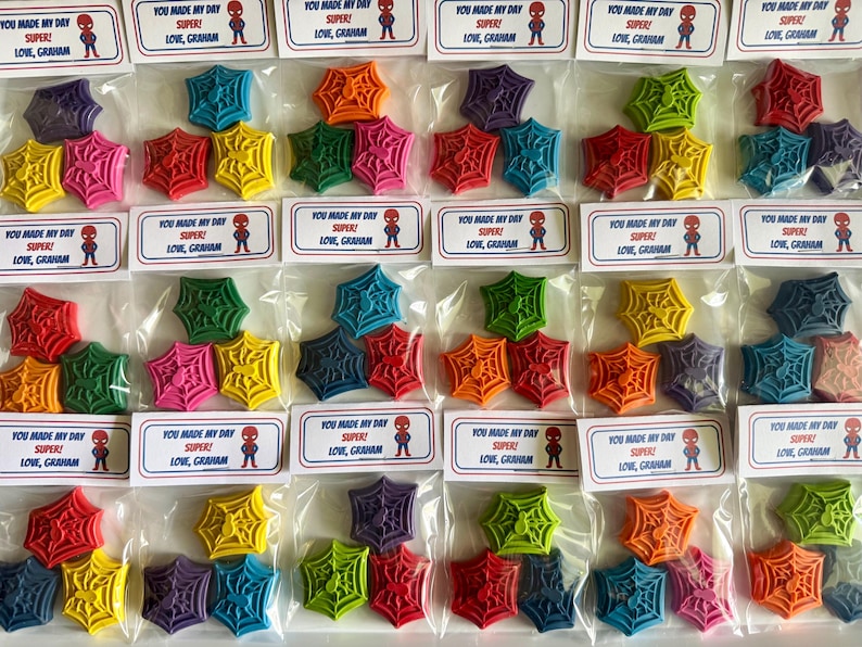 May include: Colorful spiderweb-shaped crayons in various colors, packaged in clear bags. Each bag includes a label with the text "YOU MADE MY DAY SUPER! LOVE, GRAHAM" and a Spider-Man graphic. A fun and creative craft supply.