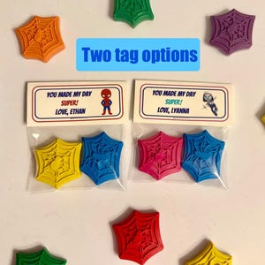 May include: Colorful Spider-Man themed party favors. The image shows various colors of spider web shaped wax crayons, with two tag options. The tags read "You made my day SUPER!" and include the names Ethan and Lyanna.