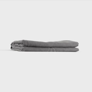 Puede incluir: Una s&aacute;bana de lino gris doblada. La s&aacute;bana est&aacute; doblada por la mitad y luego por la mitad de nuevo, creando una forma rectangular.