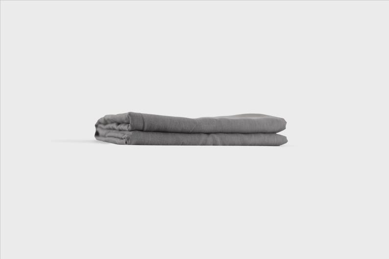 Puede incluir: Una s&aacute;bana de lino gris doblada. La s&aacute;bana est&aacute; doblada por la mitad y luego por la mitad de nuevo, creando una forma rectangular.