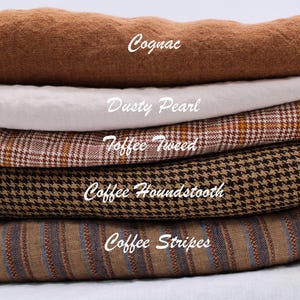 May include: A stack of folded fabric samples in various colors and patterns. The top fabric is cognac-colored, followed by dusty pearl, toffee tweed, coffee houndstooth, and coffee stripes. Each fabric has a label with its name.