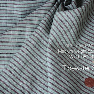 May include: Close-up of Tidewater Stripe fabric with a teal and burgundy striped pattern. The fabric is 48% linen and 52% cotton, medium weight 5.6oz/190gsm, and 58 inches wide. A penny is in the lower right corner.
