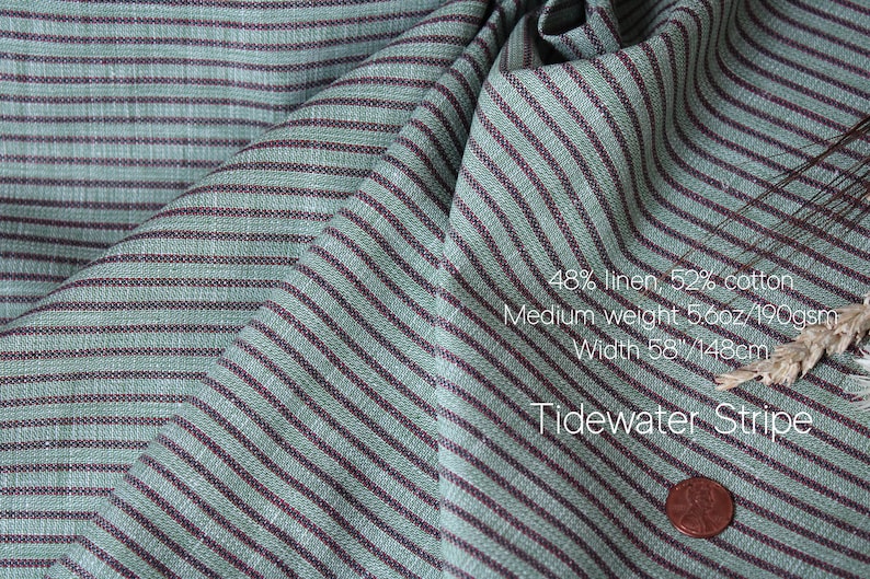 May include: Close-up of Tidewater Stripe fabric with a teal and burgundy striped pattern. The fabric is 48% linen and 52% cotton, medium weight 5.6oz/190gsm, and 58 inches wide. A penny is in the lower right corner.