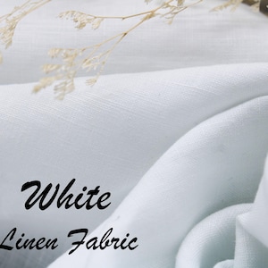 Może przedstawiać: Kawałek białej tkaniny lnianej o widocznej splocie, ułożony w miękkie fałdy. Tekst "White Linen Fabric" jest nadrukowany czarną kursywą w lewej dolnej części obrazu, w towarzystwie suszonych łodyg kwiatowych.