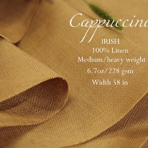 K&ouml;nnte beinhalten: Nahaufnahme eines gefalteten Stoffes in Cappuccino-Farbe. Der Text auf dem Stoff lautet "Cappuccino", "IRISH", "100% Linen", "Medium/heavy weight", "6.7oz/228 gsm" und "Breite 147 cm".