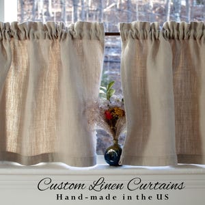 May include: A pair of natural linen cafe curtains with a gathered top, hanging in a window. The curtains are made in the USA. "Custom Linen Curtains Hand-made in the US" is written below the curtains.