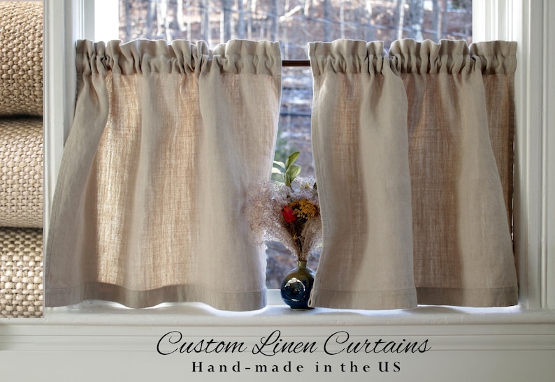 May include: A pair of natural linen cafe curtains with a gathered top, hanging in a window. The curtains are made in the USA. "Custom Linen Curtains Hand-made in the US" is written below the curtains.