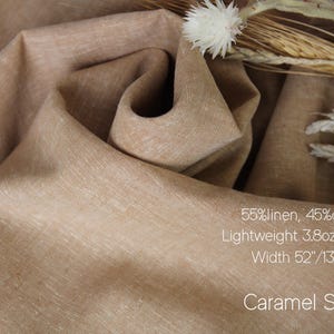 K&ouml;nnte beinhalten: Nahaufnahme eines karamellfarbenen Stoffes, 55 % Leinen und 45 % Baumwolle. Das leichte Material ist 133 cm breit. Der Text auf dem Bild lautet "Caramel Sand".