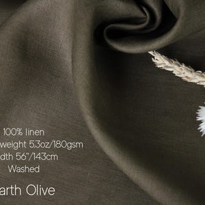 May include: Earth Olive 100% linen fabric. The medium-weight fabric is 56 inches wide. The image shows a close-up of the fabric with a textured surface and a natural drape. The fabric is a muted olive green color. The image also includes dried flowers.