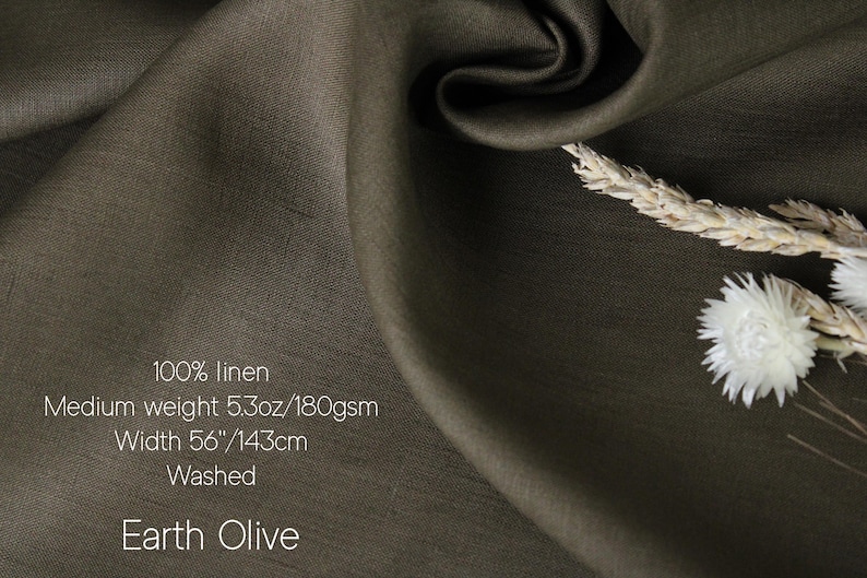 May include: Earth Olive 100% linen fabric. The medium-weight fabric is 56 inches wide. The image shows a close-up of the fabric with a textured surface and a natural drape. The fabric is a muted olive green color. The image also includes dried flowers.