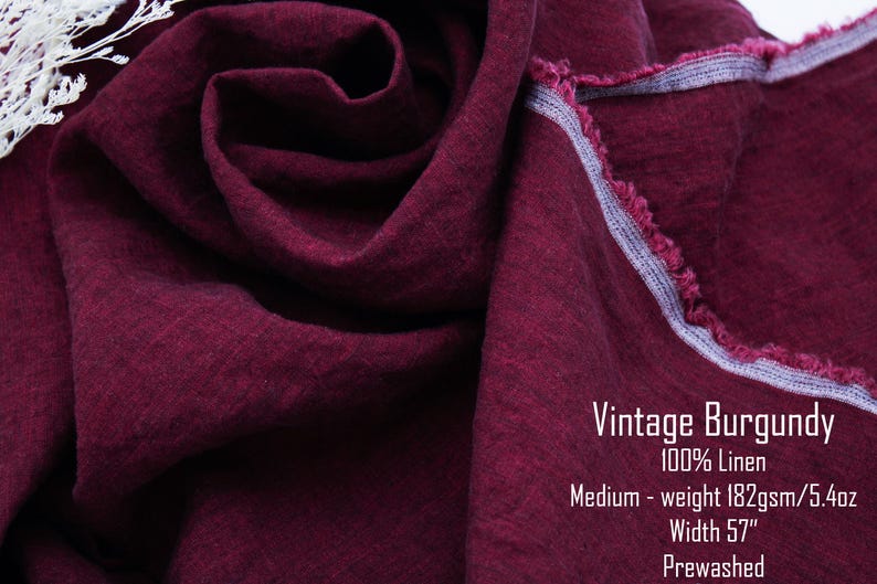 May include: A piece of deep burgundy linen fabric with a visible weave and a frayed edge. Text on the fabric reads: Vintage Burgundy, 100% Linen, Medium-weight 182gsm/5.4oz, Width 57", Prewashed. A small section of white lace is visible in the corner.
