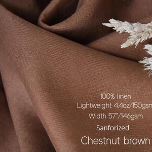 K&ouml;nnte beinhalten: Kastanienbrauner Stoff aus 100 % Leinen. Leicht, 4,4 oz/150 g/m&sup2;, Breite 146 cm. Der Stoff ist sanforisiert. Das Bild zeigt den Stoff drapiert, mit einem Zweig getrockneter Blumen.